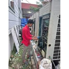 Technician inspecting outdoor HVAC equipment in a narrow service area